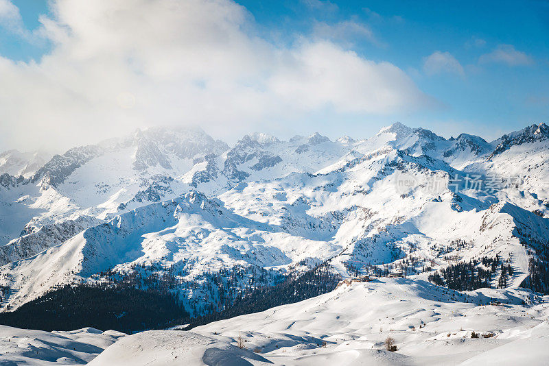 高山冬季景观与滑雪斜坡和滑雪者在一个阳光明媚的日子背景照片。阿尔卑斯山美丽的山景。冬季运动/冬季概念。自然的壁纸。
